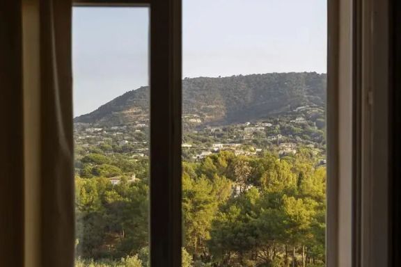 Ausblick auf grüne Hügel und Wald durch ein Fenster