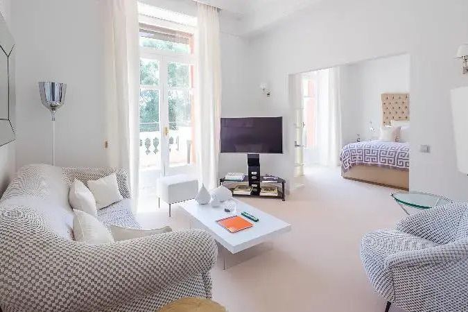 Wohnbereich einer Junior-Suite mit stilvollem Sofa, Flachbild-TV und großen Fenstern.