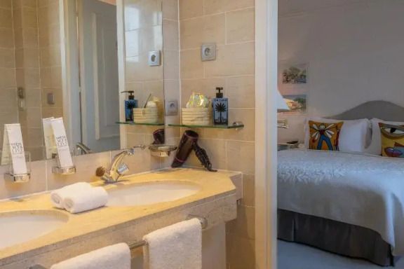 Elegantes Badezimmer im Hotelzimmer mit Doppelwaschbecken und Blick ins Schlafzimmer