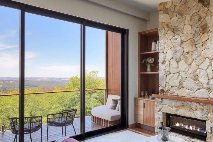 Luxuriöses Zimmer mit großem Fenster und Balkonblick auf grüne Landschaft