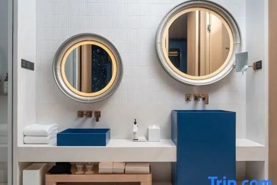Modernes Badezimmer mit blauen Waschbecken und rund beleuchteten Spiegeln in der Suite.