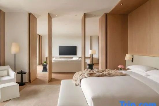 Modernes Schlafzimmer der Präsidenten Suite mit edler Holzverkleidung, Kingsize Bett und Blick in den Wohnbereich