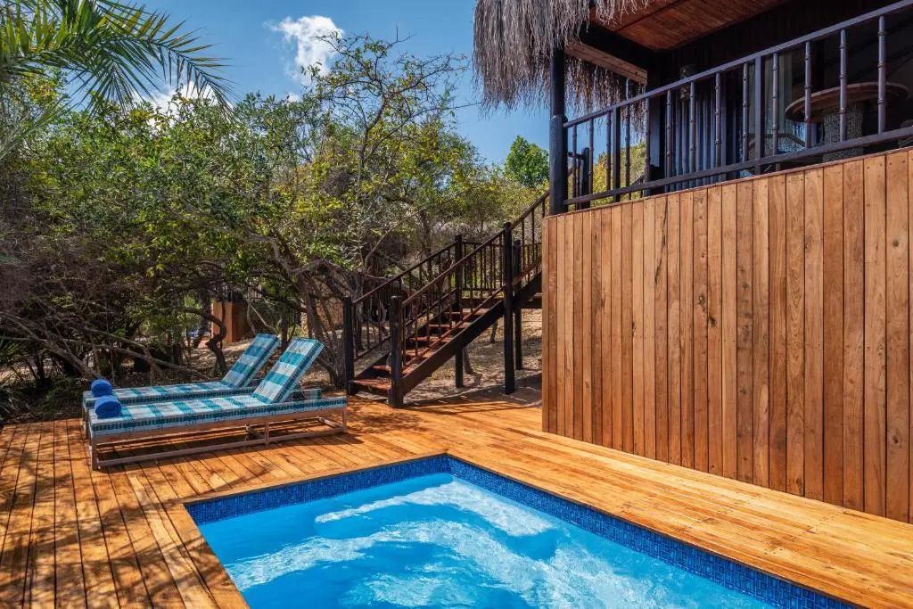 Kleiner privater Pool neben Villa mit Holzterrasse und Liegestühlen.