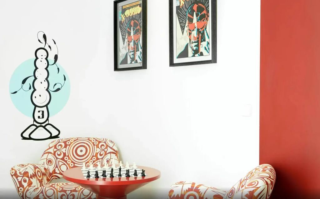 Schachspiel auf rotem Tisch mit stilvollen Sesseln und Wandkunst