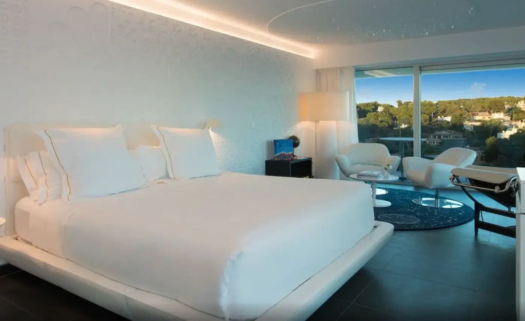 Modernes Doppelbett in einer eleganten Suite mit Meerblick und stilvoller Beleuchtung.