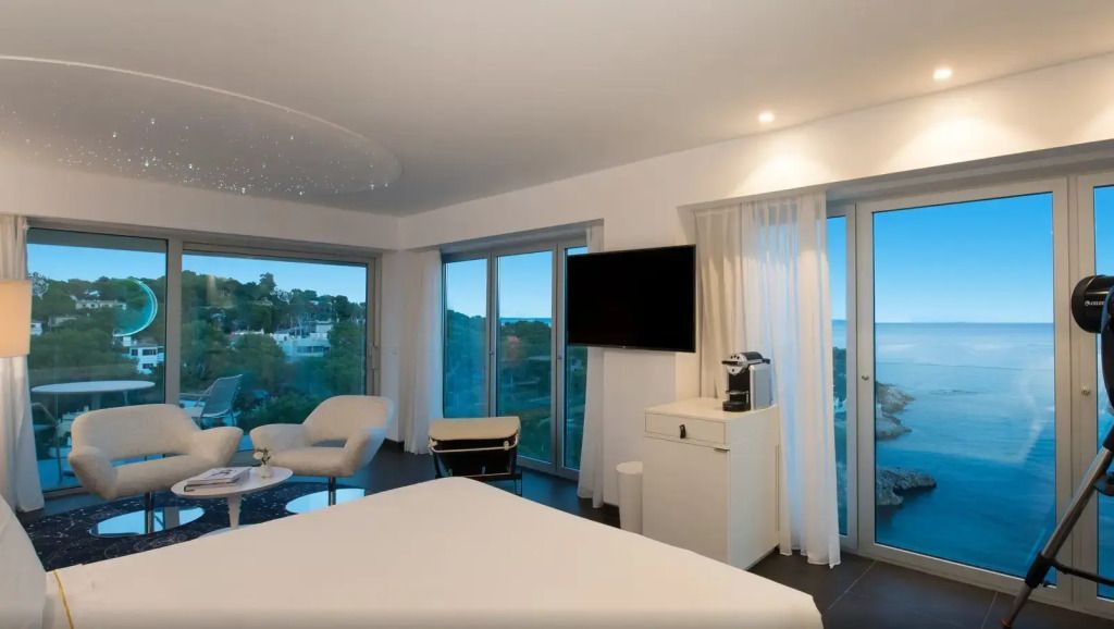 Helles Zimmer mit großem Fenster und Teilblick auf die Umgebung, ausgestattet mit TV.