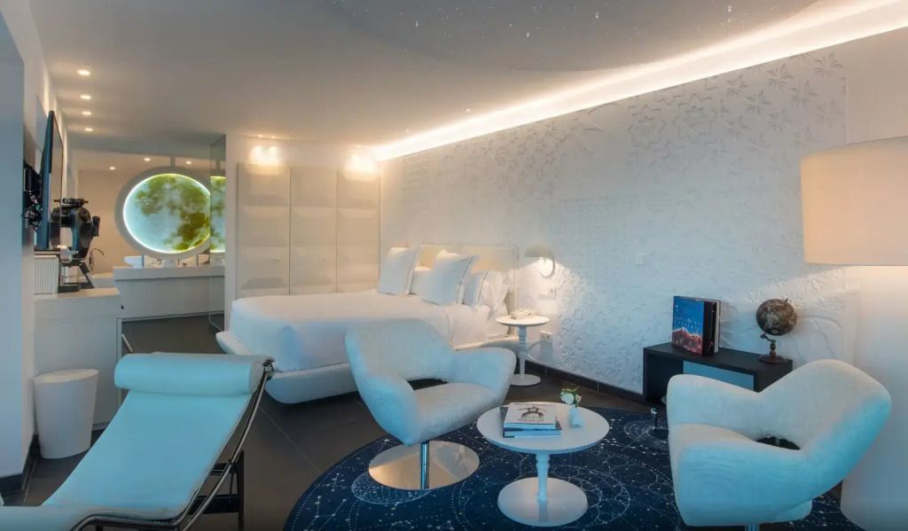 Komfortable Sitzecke neben modernem Doppelbett in stilvoller Suite.