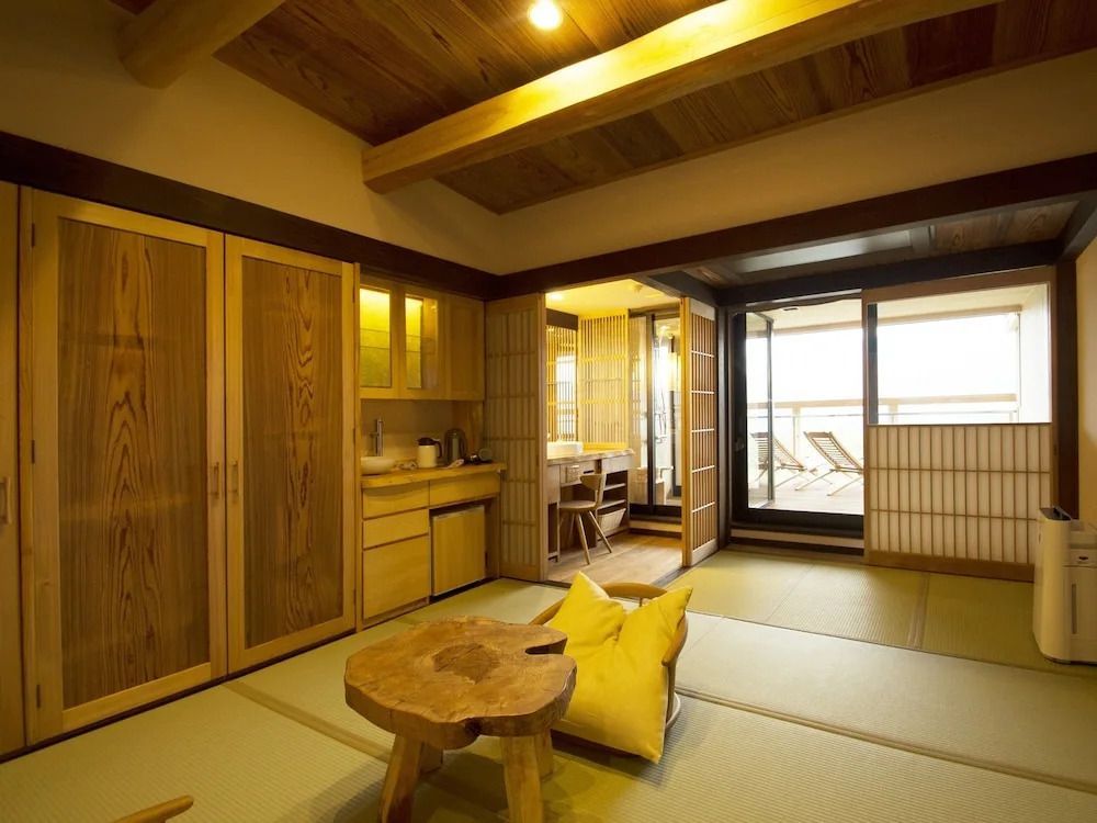 Zimmer mit traditionellen Tatami-Matten, Tisch und Zugang zu einem Balkon.