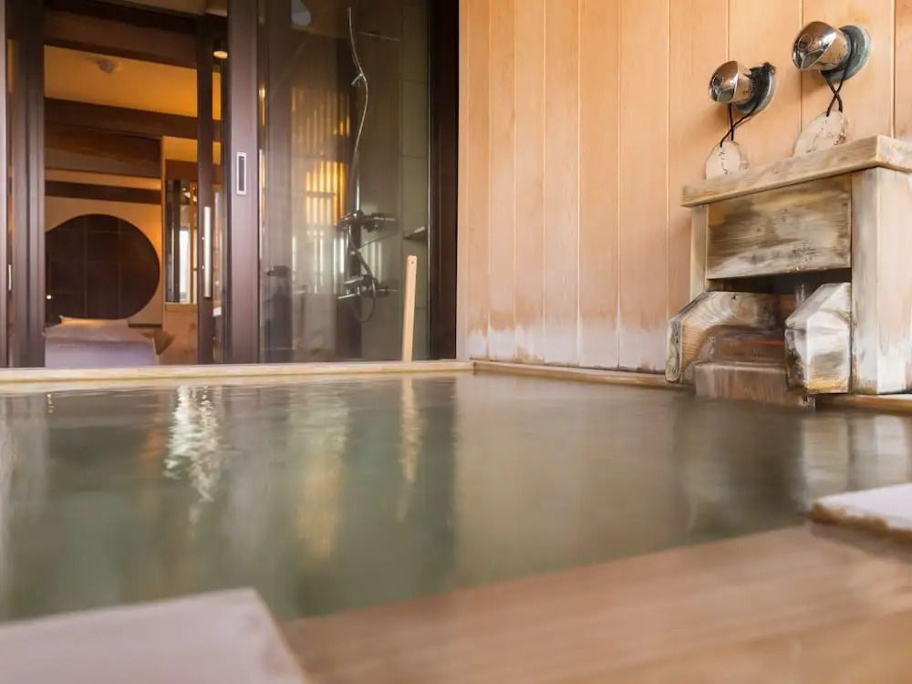 Privates Onsen-Bad mit Holzvertäfelung im Hintergrund.