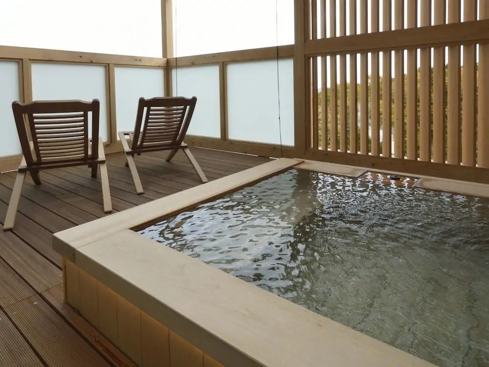 Privater Außenbereich mit Holzbad und Liegestühlen.