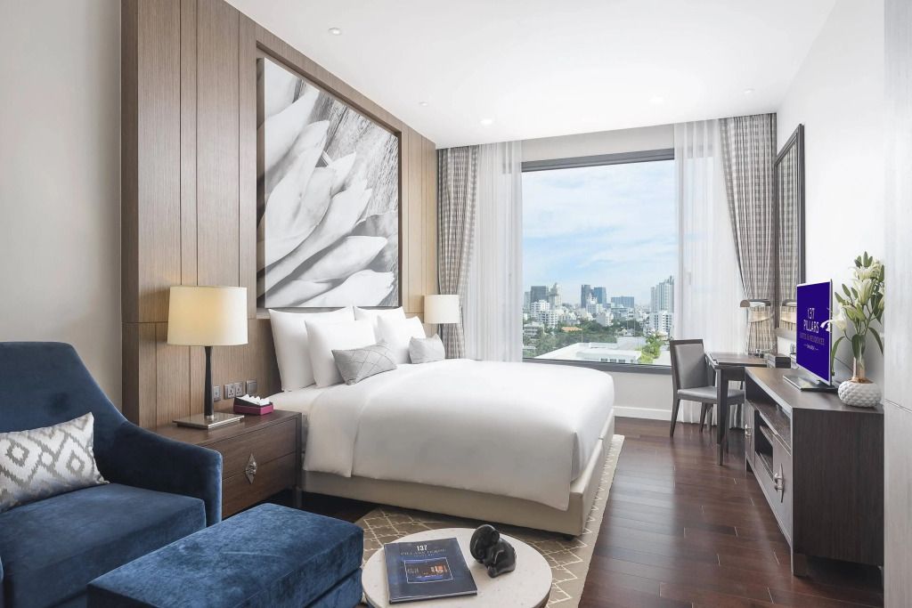 Helles Schlafzimmer mit Doppelbett und großem Fenster mit Stadtblick.