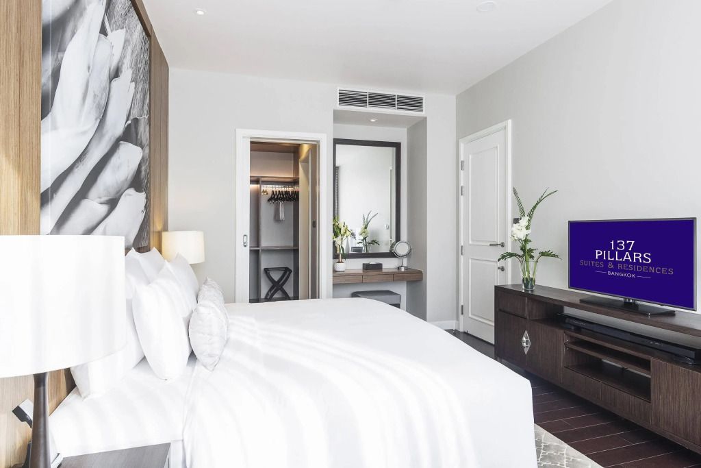 Schlafzimmer mit Doppelbett, Fernseher und Durchgang zum Ankleidebereich.