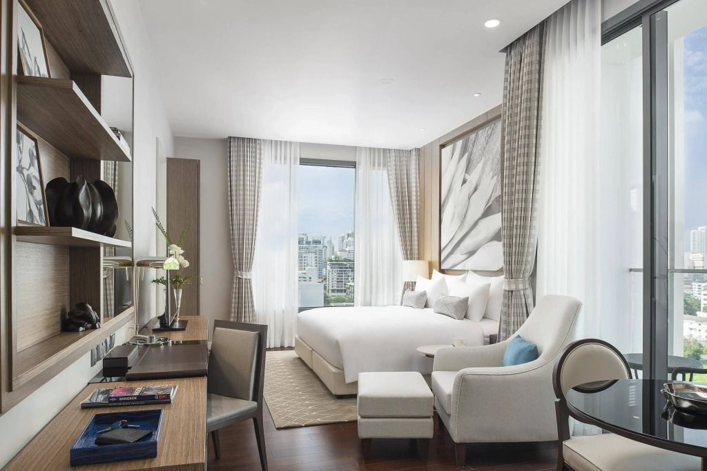 Helles Studio mit Doppelbett, stilvollen Sesseln und Aussicht auf die Stadt