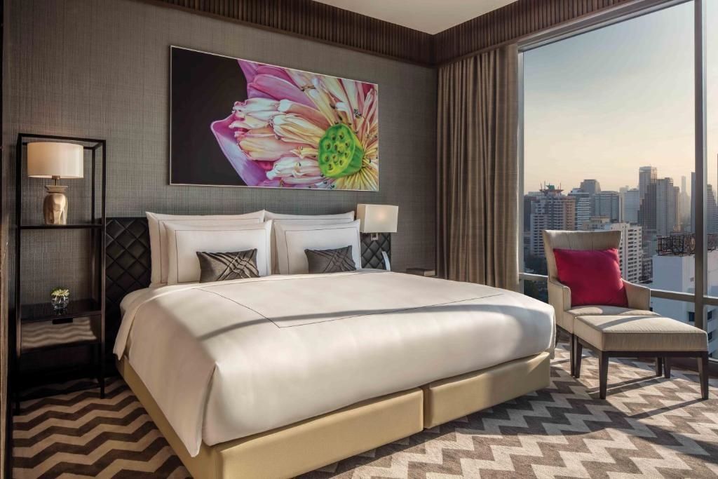 Helles Schlafzimmer der Rattanakosin Suite mit großem Bett und Stadtblick.