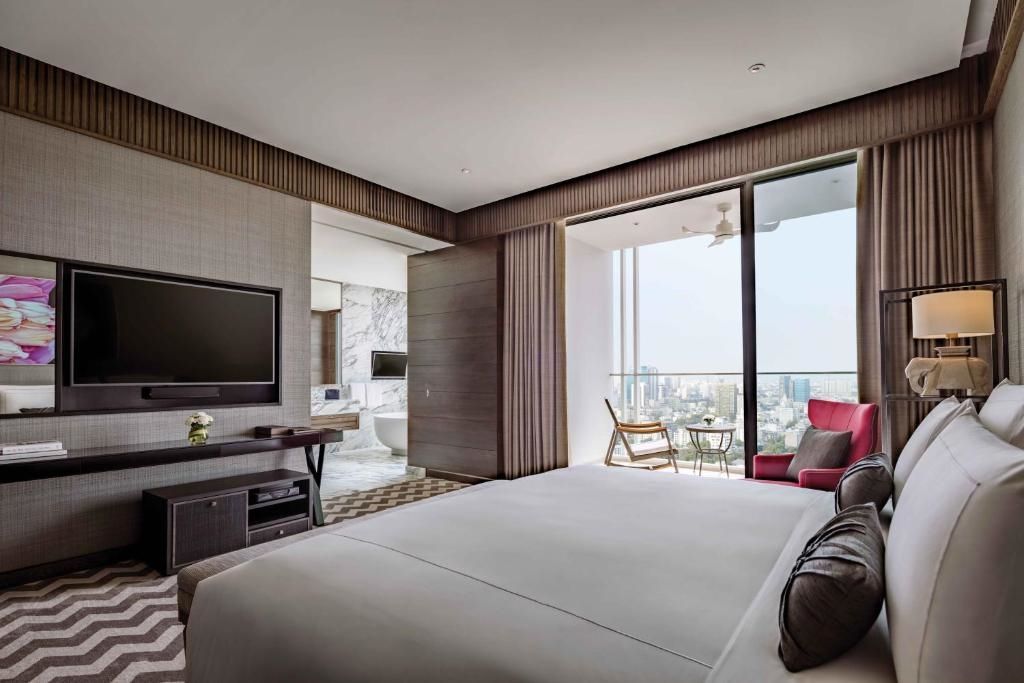 Sukhothai Suite mit großem Bett und Balkon mit Ausblick auf Bangkok.