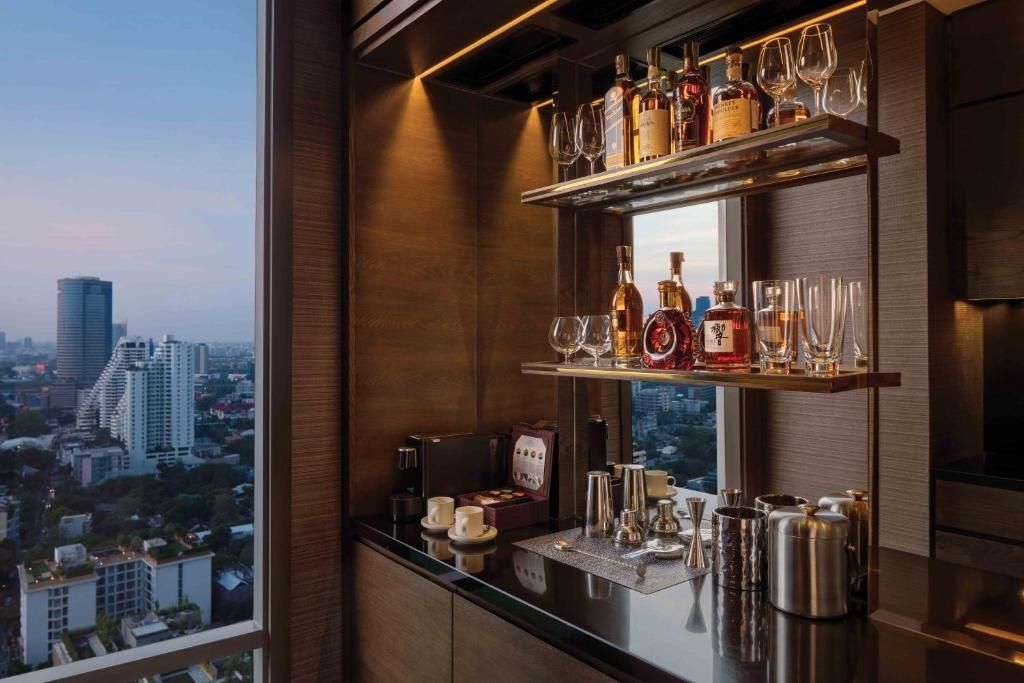 Exklusive Minibar mit erlesenen Spirituosen und Gläsern vor Stadtpanorama