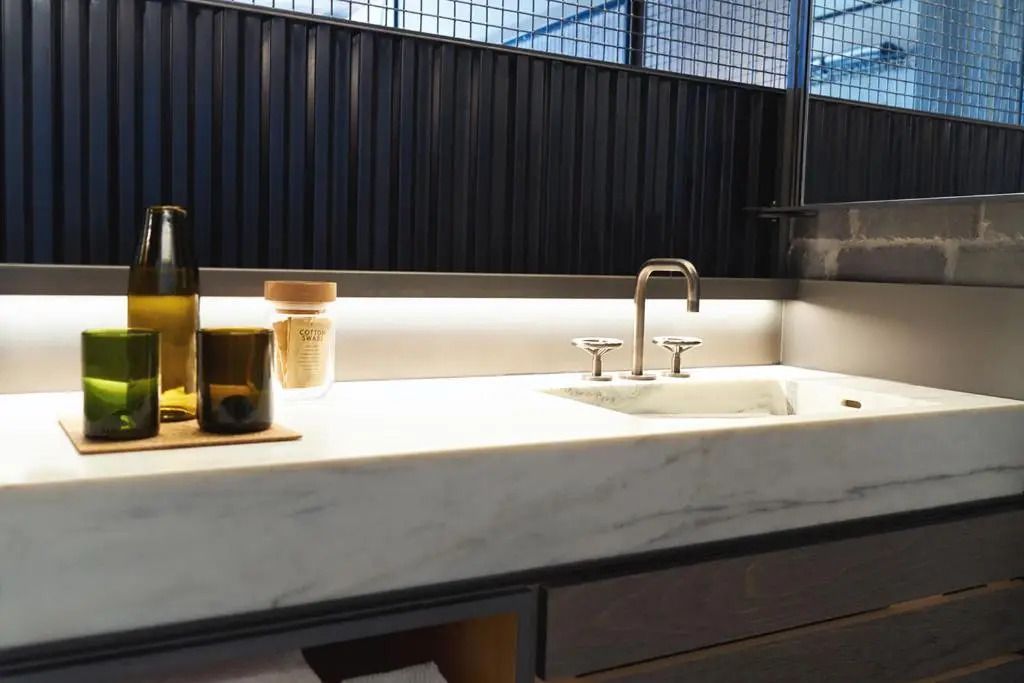 Modernes Badezimmer mit Waschbecken aus weißem Marmor und eleganter Beleuchtung