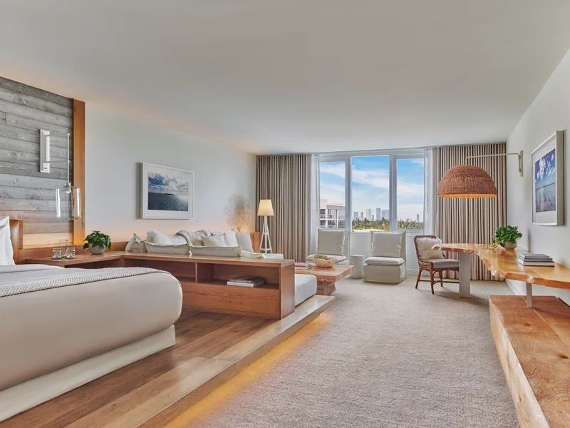 Helles Wohnzimmer mit großen Fenstern und moderner Einrichtung im Hotelzimmer.