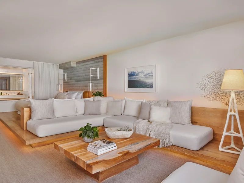 Moderne Sitzecke mit hellem Sofa und Holztisch im Hotelzimmer.