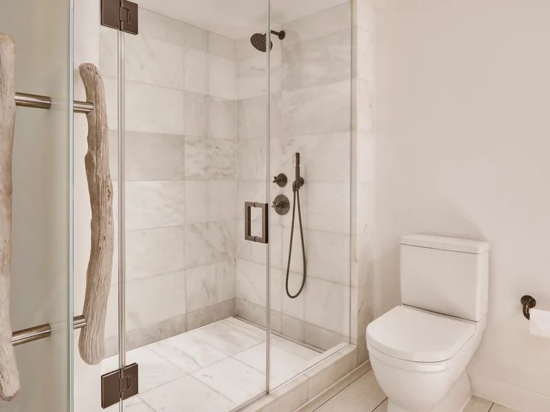 Moderne Dusche in Marmoroptik mit eleganter Glasabtrennung im Hotelbad.