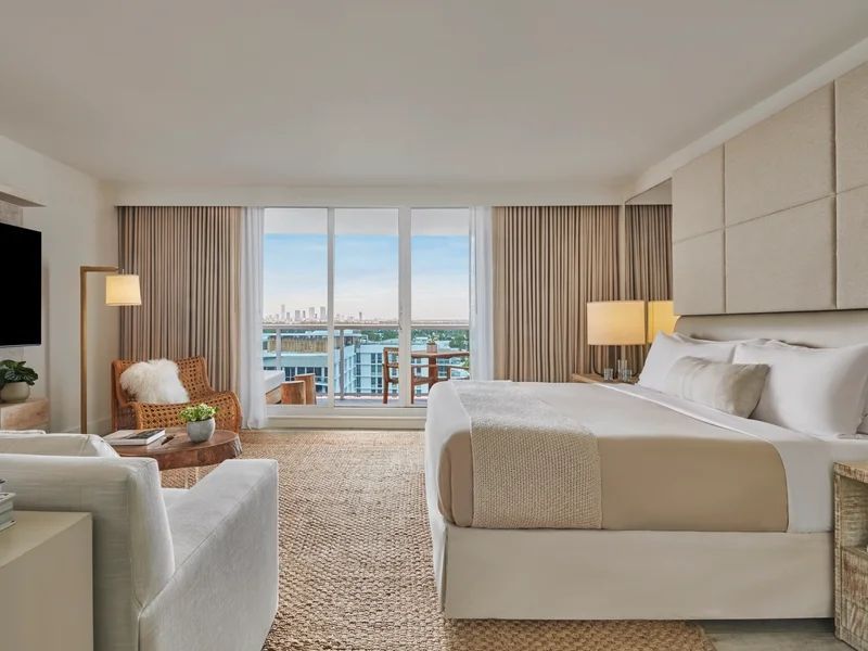 Helles Doppel Studio Suite mit großem Bett und Blick auf die Stadt durch große Fenster