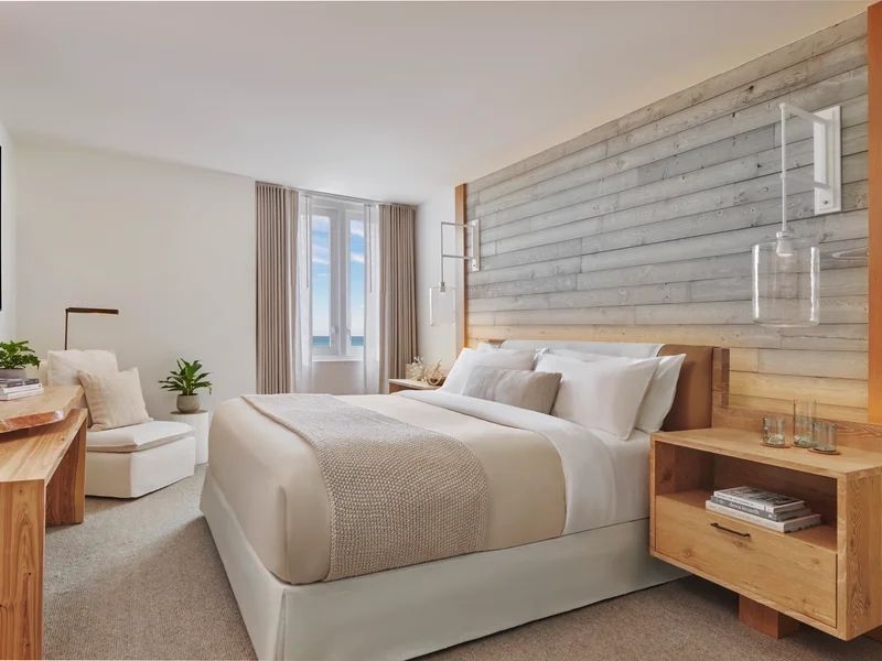 Helles Schlafzimmer mit Doppelbett, Holzdetails und großen Fenstern