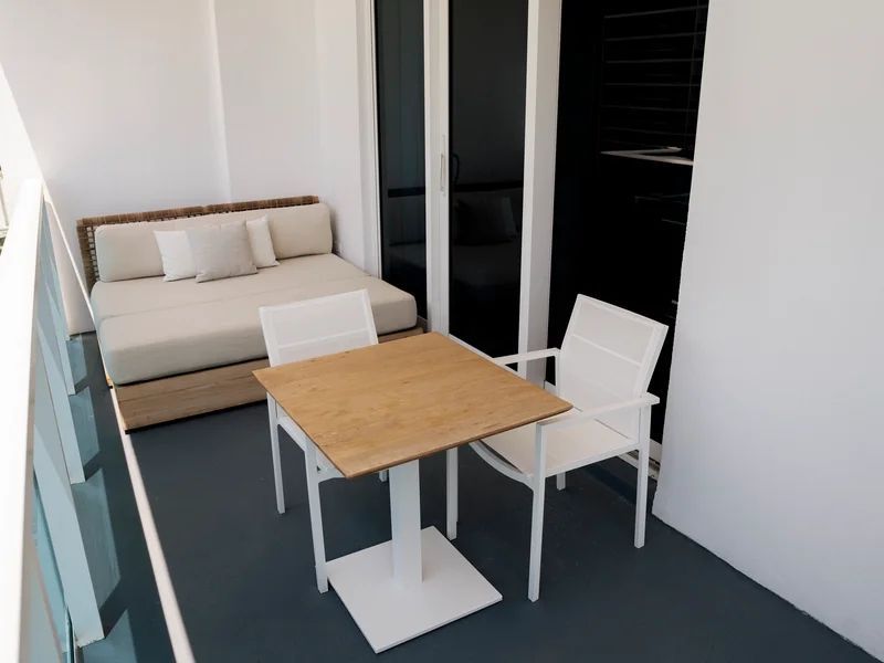 Gemütlicher Balkon mit Tisch, zwei Stühlen und Sofa mit Ausblick auf die Stadt.