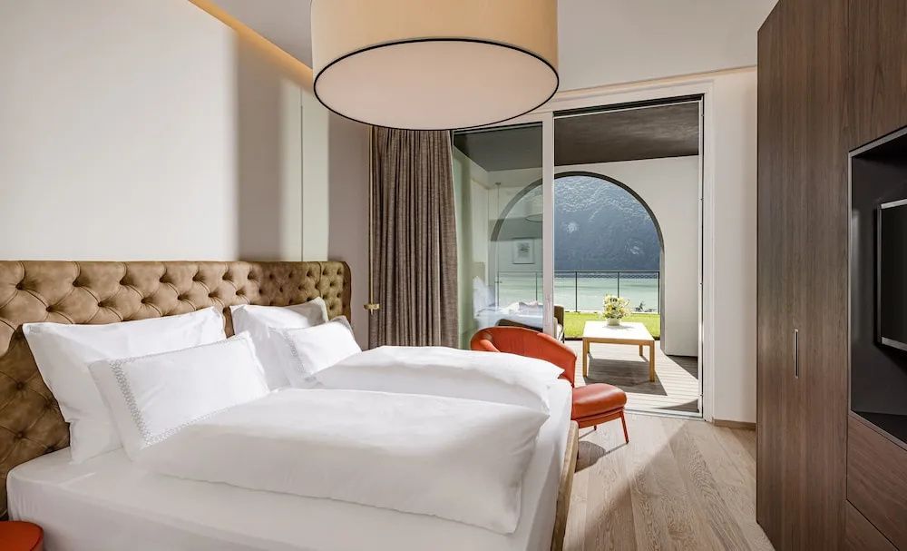Hell eingerichtetes Schlafzimmer mit Doppelbett und Zugang zum Balkon