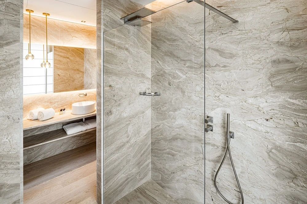 Badezimmer mit bodengleicher Glasdusche und hellen Steinwänden