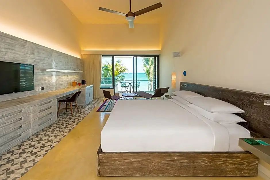 Hotelzimmer mit Doppelbett, langem Schreibtisch und Balkon mit Blick auf das Meer.