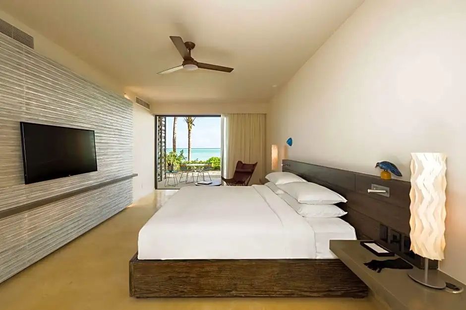 Schlafzimmer mit großem Bett, Holzdekor und Terrasse mit Blick auf Strand und Meer.