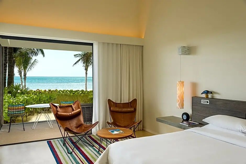 Sitzecke im Zimmer mit zwei Ledersesseln und Blick auf grüne Pflanzen und das Meer.