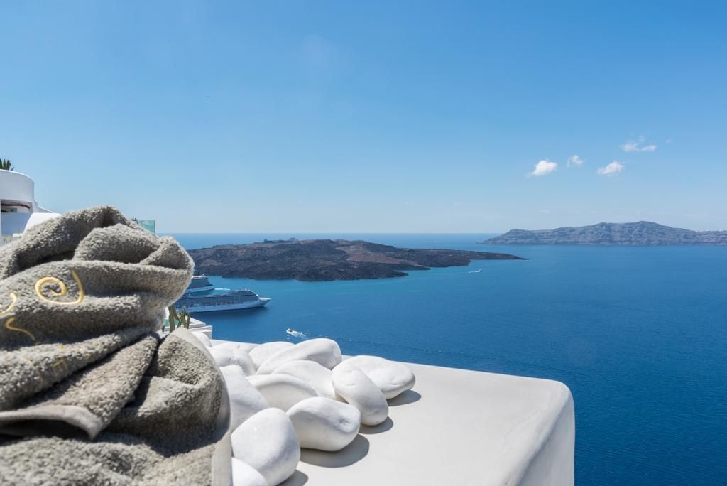 Blauer Ozeanblick mit Felsen und ein luxuriöses Kreuzfahrtschiff im Hintergrund