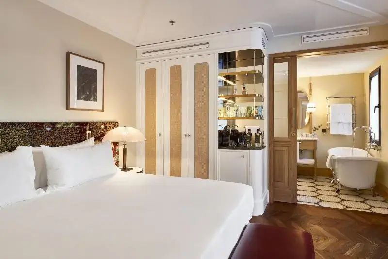Helles Hotelzimmer mit großem Doppelbett, weiße Einbauschränke und Blick in das angrenzende Badezimmer.