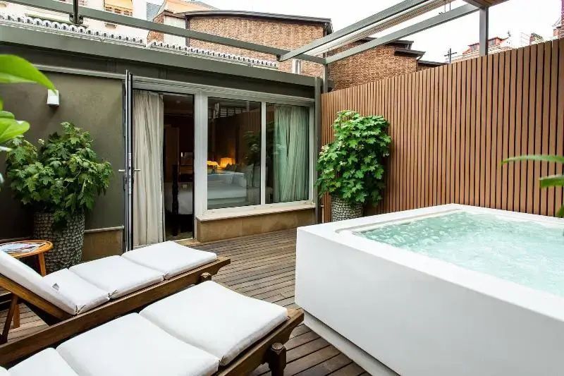 Terrasse mit zwei Liegestühlen und Whirlpool direkt vor den Glastüren der Suite.