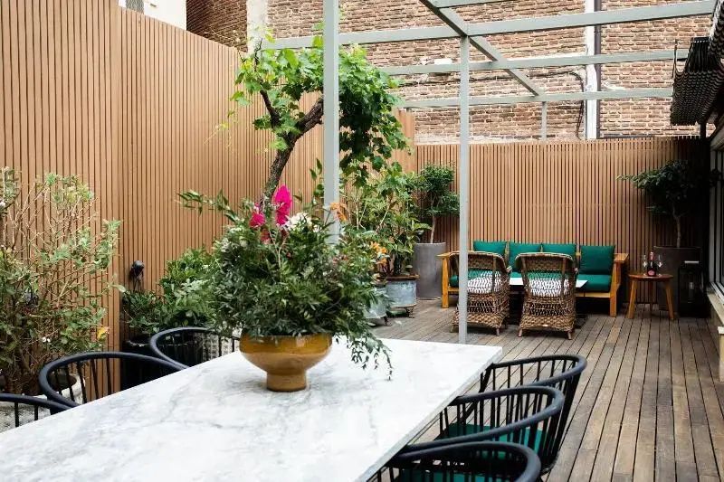 Terrasse mit großem Marmortisch, Stühlen, Holzverkleidung und Topfpflanzen.