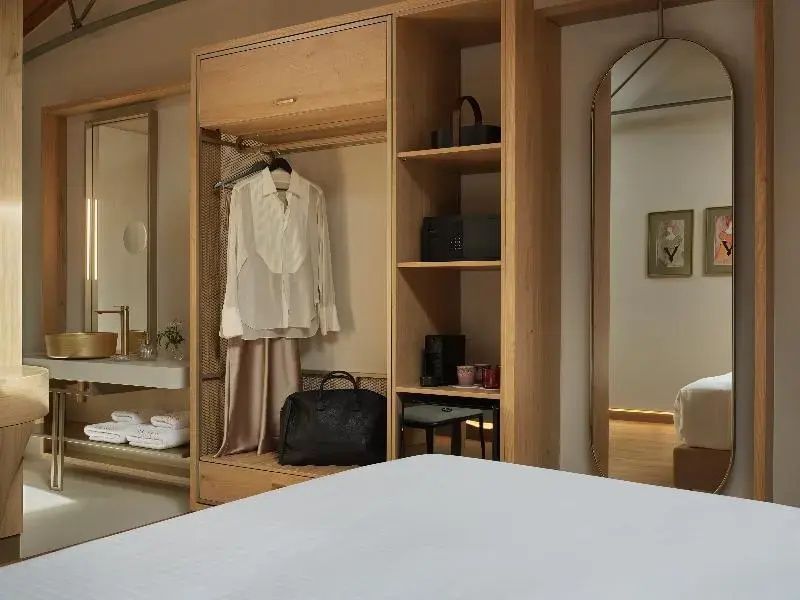 Offener Kleiderschrank aus hellen Holzleisten mit Kleidung und Accessoires im Zimmer.