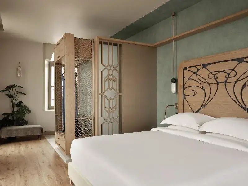 Schlafzimmer mit modernem Doppelbett und getrenntem Ankleidebereich aus Holz.