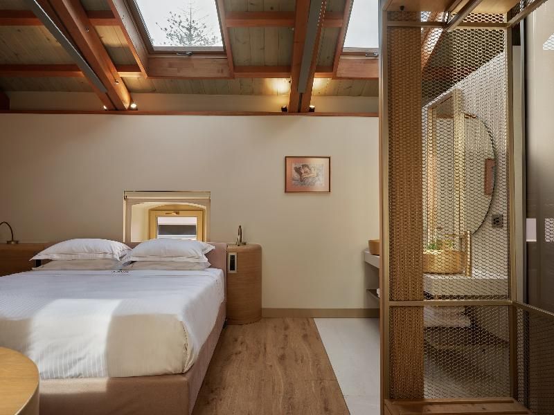Doppelbett in einem Zimmer mit Holzboden und Dachfenstern in der Holzdecke.
