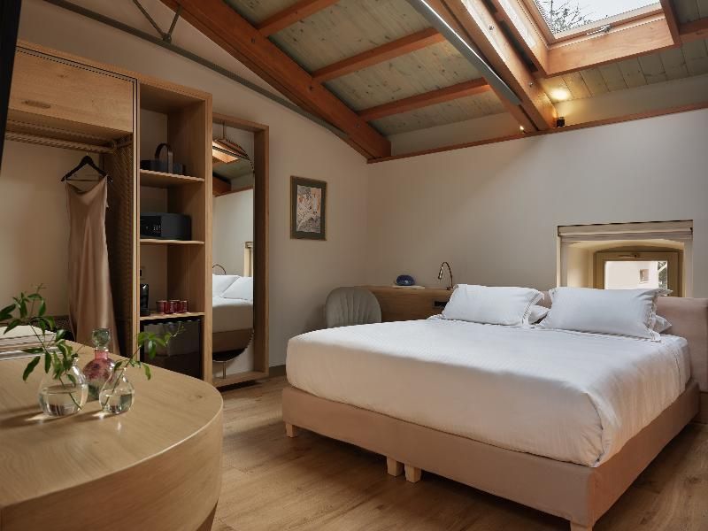 Hotelzimmer unter einer Dachschräge mit Holzbalken, Doppelbett und Dachfenster.