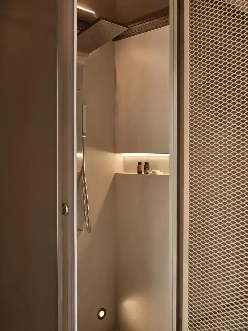 Blick in eine Dusche mit beleuchteter Wandnische und Pflegeprodukten.