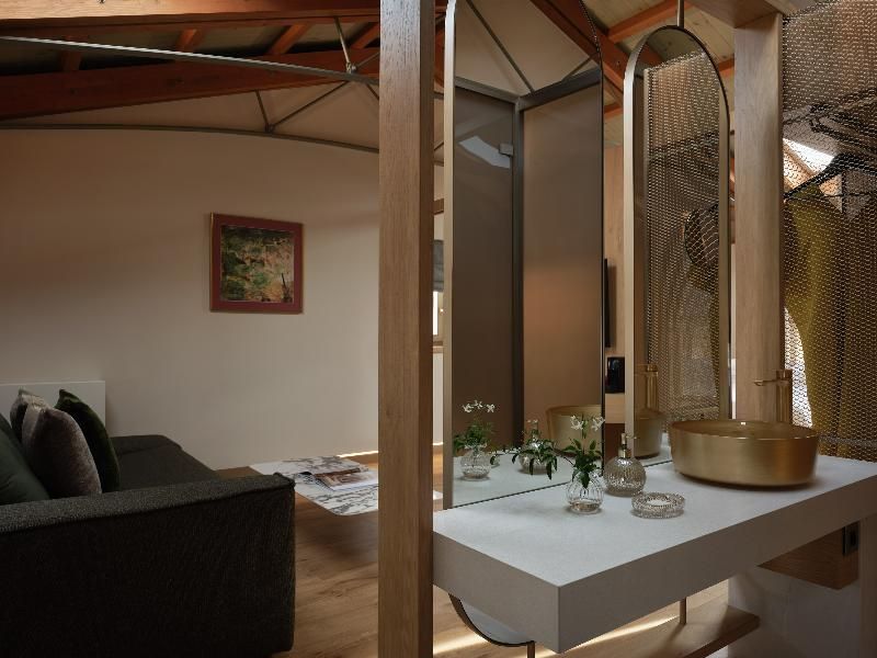 Waschplatz mit ovalen Spiegeln und goldenem Waschbecken im Hotelzimmer.