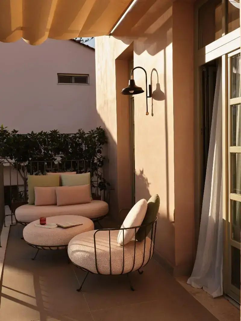 Terrasse mit modernen Sitzmöbeln, Kissen und einer schwarzen Wandleuchte.