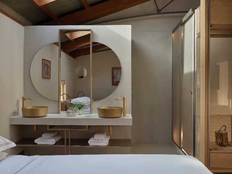 Badezimmerbereich mit zwei goldenen Waschbecken und rundem Spiegel.