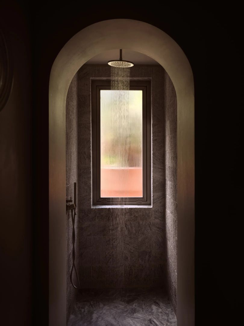 Moderne Regendusche in einer Rundbogennische mit Sichtfenster im naturnah gestalteten Badezimmer.