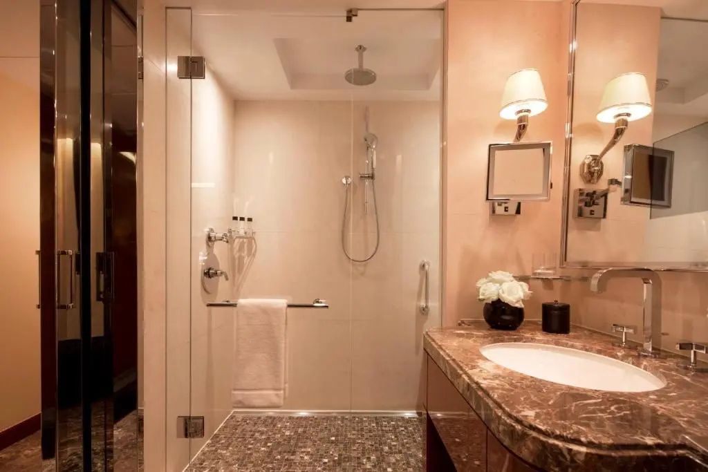 Modernes Badezimmer mit einer begehbaren Glasdusche und einem Waschtisch aus Marmor.