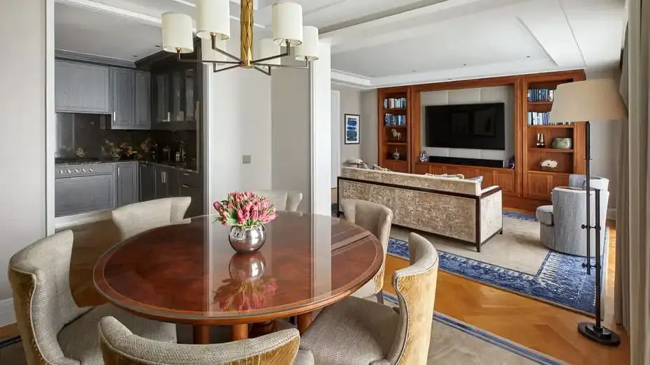 Runder Esstisch mit Tulpenstrauß und dahinter liegender Wohnbereich mit Sofa und Fernseher.