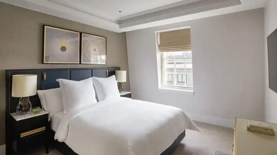 Helles Hotelzimmer mit Doppelbett, Bildern an der Wand und einem kleinen Fenster.