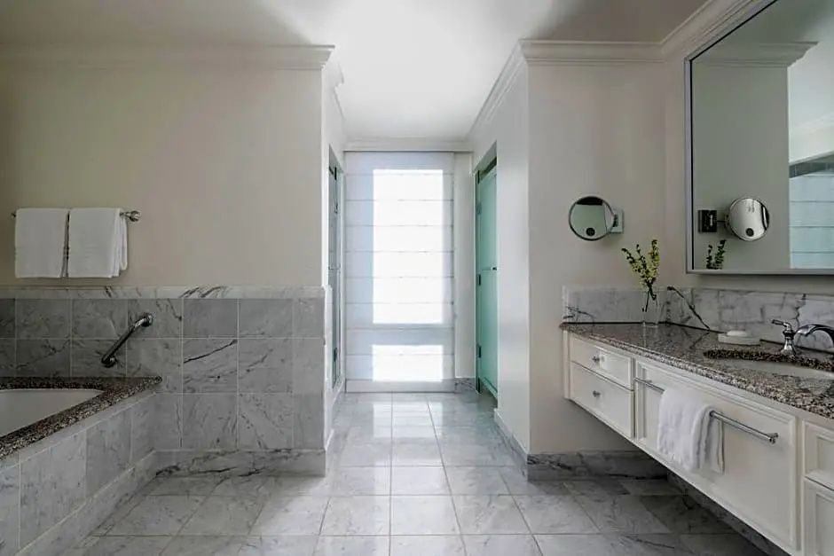 Geräumiges Badezimmer mit weißem Marmorboden, Waschtisch und hellem Fensterbereich.