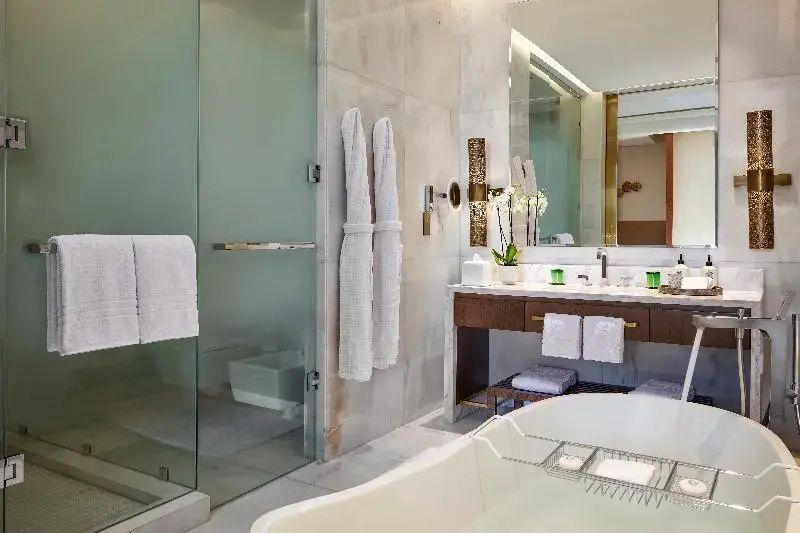 Badezimmer mit weißer Badewanne, Glasdusche und Waschtisch mit Spiegel.